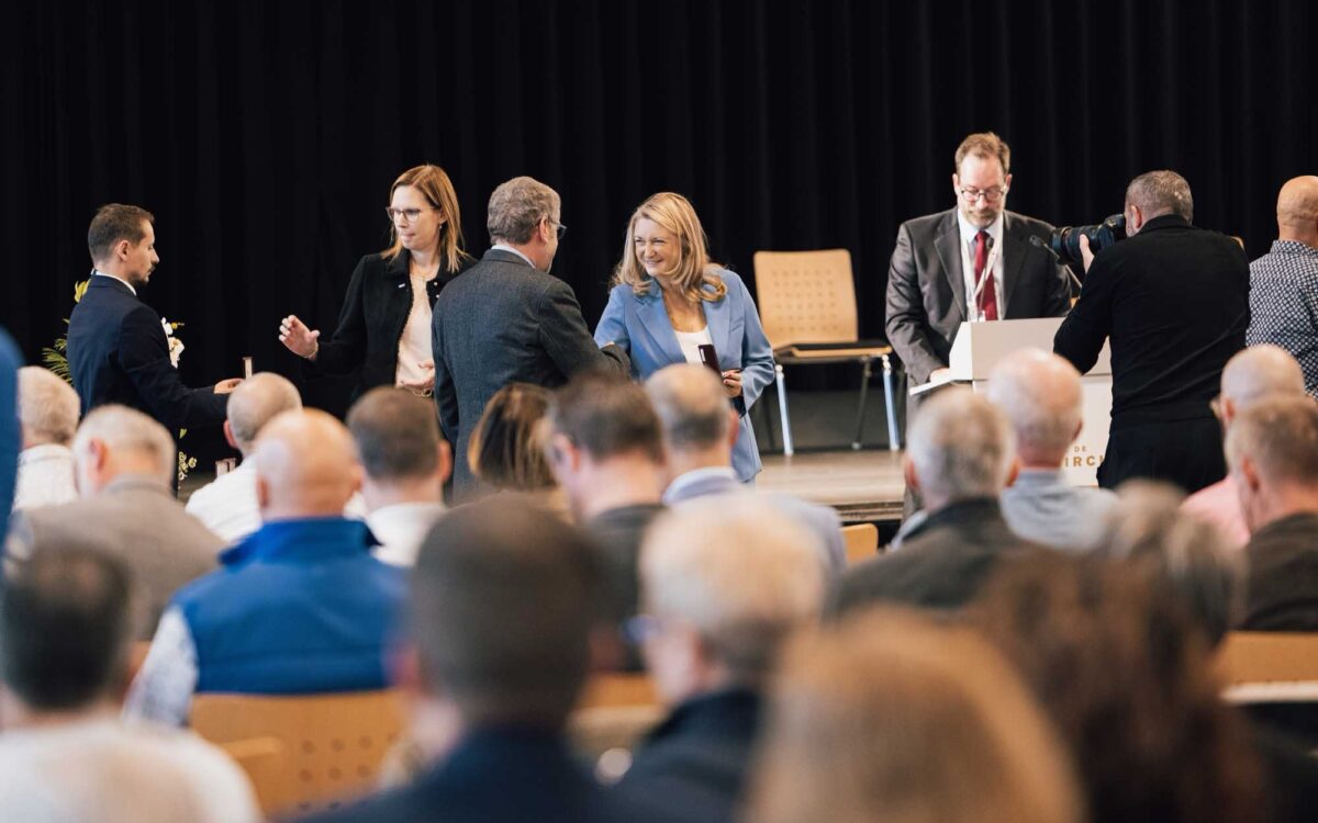 Großherzogin Stephanie von Luxemburg überreicht in Diekirch eine Medaillenschachtel an verdiente Blutspender - lächelnd im hellblauen Blazer, umgeben von Gästen.