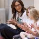 Königin Mary in weißem T-Shirt und Brille sitzt lächelnd auf dem Turnhallenboden und klatscht mit Kindern beim Antibulli-Jubiläum — Photo: Mary Fonden