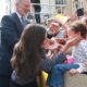 König Felipe VI. lächelt, während Königin Letizia in einer blaugrauen Jacke ein kleines Mädchen mit rosa Brille in einer jubelnden Menge mit spanischen Fahnen in Ceuta begrüßt - Photo: @casareal.es