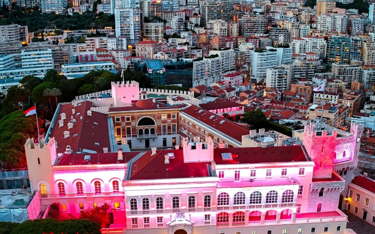 Aerial view of the Prince's Palace of Monaco glowing pink and red at dusk above the old town - Photo: Michaël Alesi / Palais princier