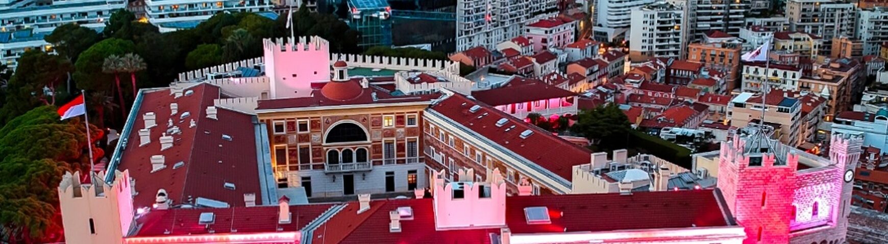 Aerial view of the Prince's Palace of Monaco glowing pink and red at dusk above the old town - Photo: Michaël Alesi / Palais princier