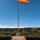 Die spanische Nationalflagge weht an einem Fahnenmast über den gepflegten Gärten des Palacio de la Zarzuela bei strahlend blauem Himmel — Photo: @casareal.es