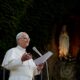 Papst Leo XIV. in Weiß am Mikrofon vor einer nächtlich erleuchteten Mariengrotte — Photo: @pontifex