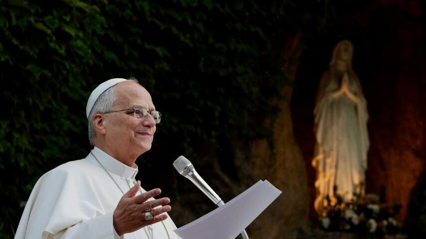 Papst Leo XIV. in Weiß am Mikrofon vor einer nächtlich erleuchteten Mariengrotte — Photo: @pontifex