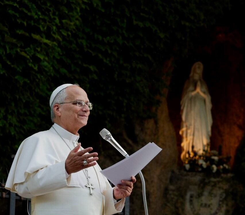 Papst Leo XIV. in Weiß am Mikrofon vor einer nächtlich erleuchteten Mariengrotte — Photo: @pontifex