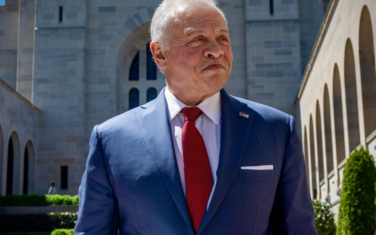 König Abdullah II. von Jordanien im dunkelblauen Anzug mit roter Krawatte und Jordanien-Anstecker im Sonnenschein in Canberra beim Staatsbesuch in Australien - Photo: @rhcjo