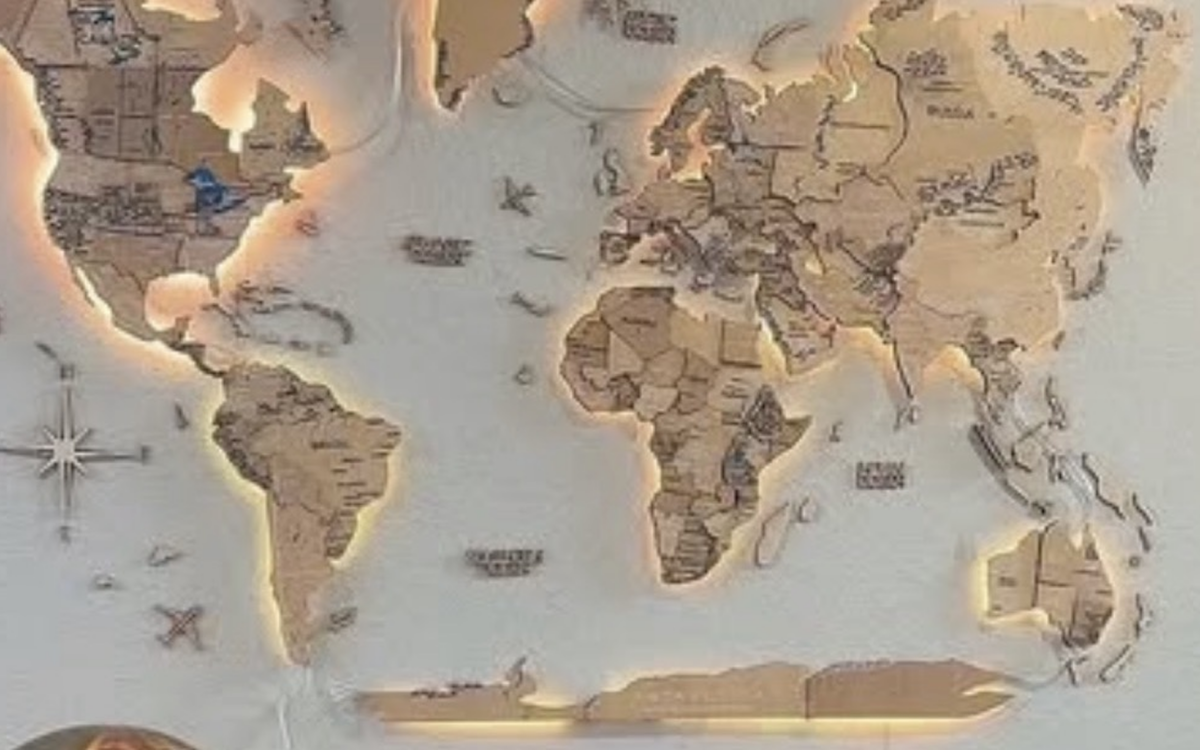 Beleuchtete hoelzerne Weltkarte an einer Wand mit warm umrandeten Kontinenten, als Symbol fuer weltweites Reisen nach New York City im Jahr 2027.