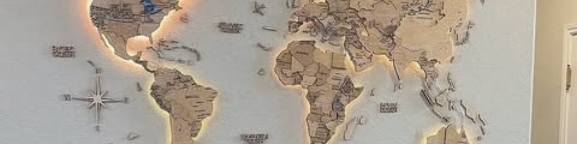 Beleuchtete hoelzerne Weltkarte an einer Wand mit warm umrandeten Kontinenten, als Symbol fuer weltweites Reisen nach New York City im Jahr 2027.