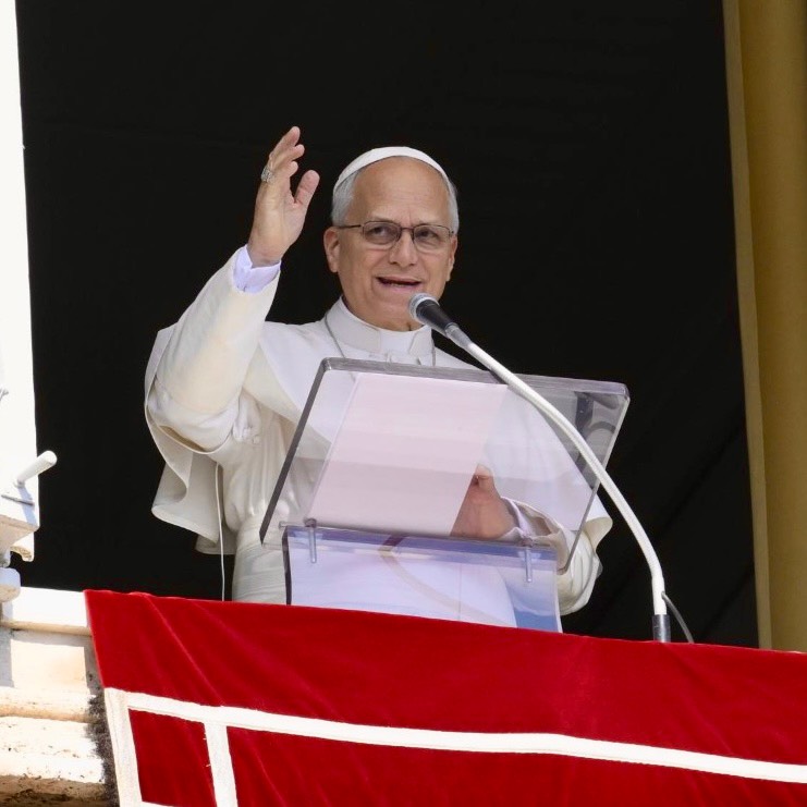 Papst Leo XIV lächelt und winkt vom Fenster des Apostolischen Palastes, Mikrofon und rotes Papstbanner im Bild - Photo: @pontifex