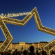 Der Weihnachtsmarkt vor dem hell erleuchteten Schloss Schoenbrunn in Wien in der Abenddaemmerung.