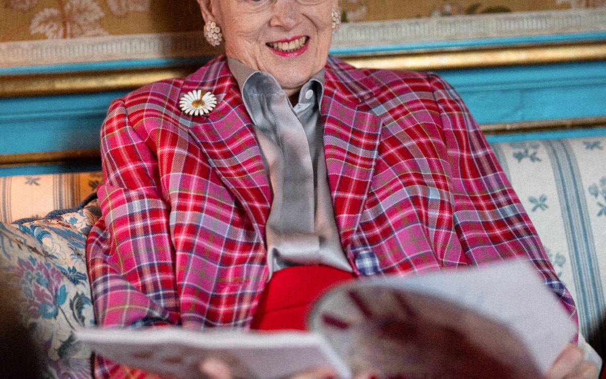 Queen Margrethe of Denmark smiling while browsing magazines at Fredensborg Palace — Photo: Kongehuset