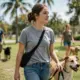 Freiwillige der Brady Hunter Foundation mit lächelndem Tierheim-Hund an der Leine im sonnigen Miami Park mit Palmen