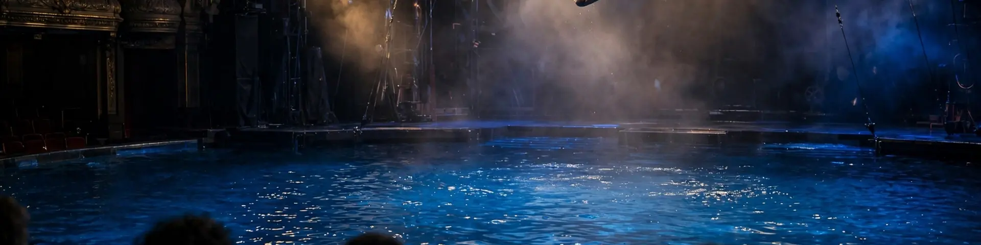 Luftakrobatin über einem riesigen Wasserbecken während einer Cirque-du-Soleil-artigen Aquatik-Show vor Theaterpublikum