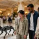 Vierbeiniger Roboterhund begleitet laechelnde Touristen durch die prunkvolle Lobby eines Luxusresorts in Macau