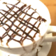 Eine dampfende Tasse heisse Schokolade mit Sahne und Marshmallows an einem gemuetlichen Morgen.